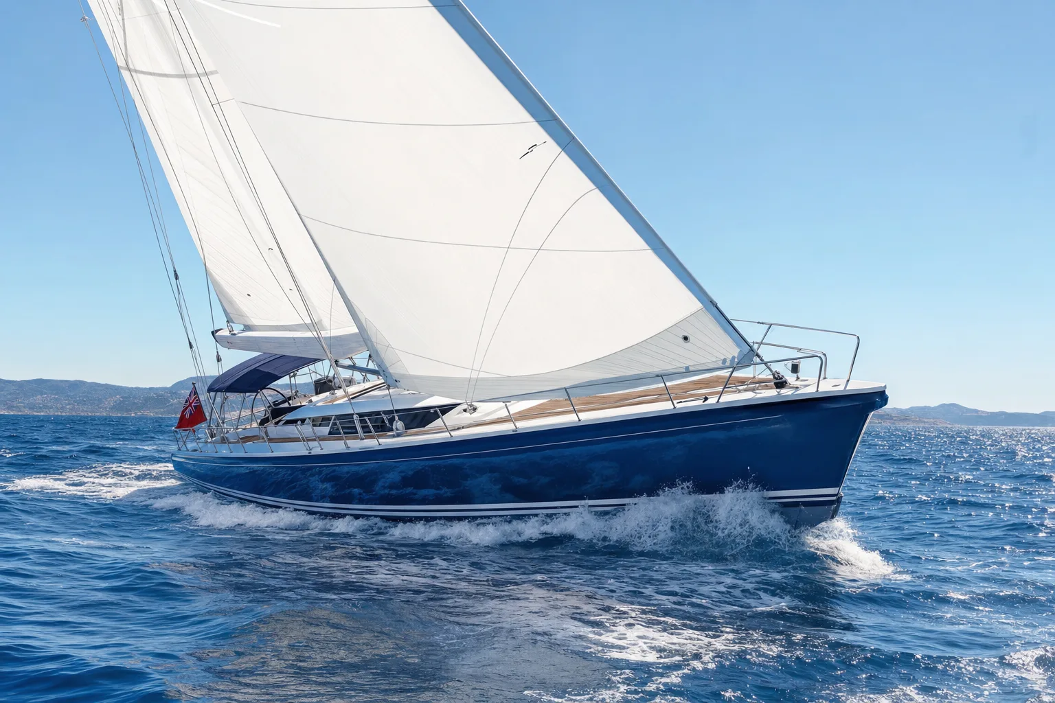 A large sailing yacht under full sail in bright open water